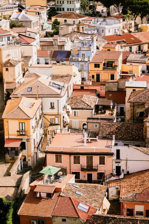 Close-packed terracotta rooftops of a hillside town, balconies and awnings stepping down the slope.